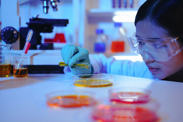 Asian female scientist passionately conducts experiments in a laboratory, surrounded by petri...