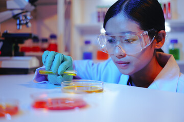 Asian female scientist passionately conducts experiments in a laboratory, surrounded by petri...