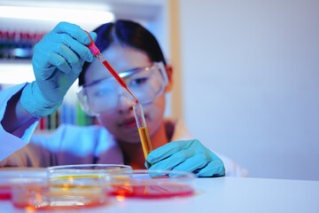 Asian female scientist passionately conducts experiments in a laboratory, surrounded by petri...