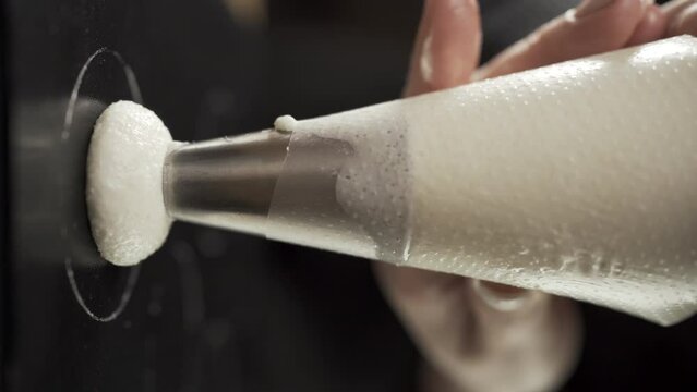 Close-up of chef hands squeezing the dough for macaroons form cooking bag. Process of making macaroon, french dessert. Food industry. Confectionery and baking concept