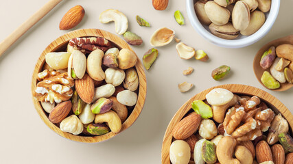 Mixed nuts in wood bowl on beige background