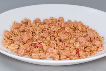 Dry muesli with dried fruits on dish, side view