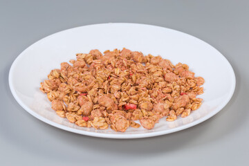 Dry muesli with dried fruits on dish, side view
