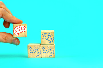  Wooden cubes with Brains icons on the background. Hand takes a cube with a Brain symbol.