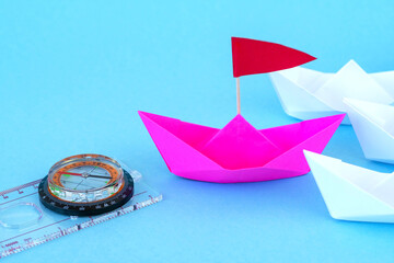 Paper Boats With Compass. paper ship leading among group of ships on background.