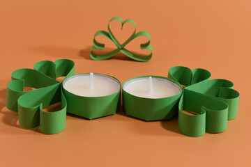 Four-leaf clover and candles on peatch background. St. Patrick's Day