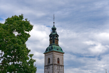 Fototapeta na wymiar Scenic view of church tower at Slovenian City of Skofja Loka on a cloudy summer day. Photo taken August 9th, 2023, Škofja Loka, Slovenia.