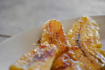 Fried banana plate on top of white wooden table.