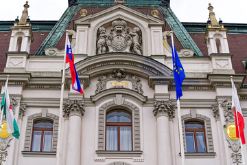 Fototapeta na wymiar Town hall decorated with flags and clock tower at the old town of City of Ljubljana on a cloudy summer day. Photo taken August 9th, 2023, Ljubljana, Slovenia.