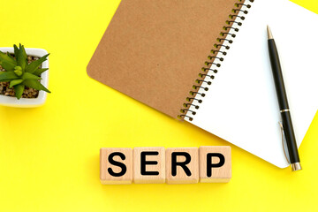 Notepad and pen on the background. Wooden cubes with word SERP.