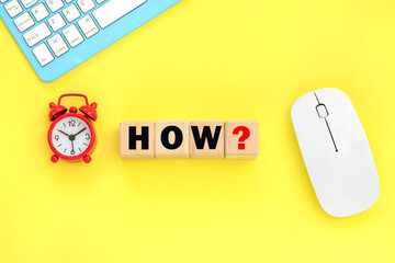 Alarm clock, keyboard, mouse on the background. Wooden cubes with word how.