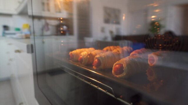 Baking sausage in dough on baking sheet in the oven, process of preparing sausages in dough at home