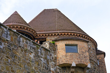 Looking up stone wall and tower with loophole of Castle of Ljubljana on a cloudy summer day. Photo taken August 9th, 2023, Ljubljana, Slovenia.