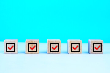  Check mark on wooden blocks, blue background with copy space.