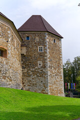 Looking up stone wall and tower with loophole of Castle of Ljubljana on a cloudy summer day. Photo taken August 9th, 2023, Ljubljana, Slovenia.