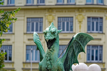 Fototapeta premium Close-up of green bronze dragon sculpture at famous Dragon Bridge City of Ljubljana on a cloudy summer day . Photo taken August 9th, 2023, Ljubljana, Slovenia.