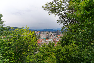 Aerial view of City of Ljubljana seen from Sance castle hill with mountain panorama in the background on a cloudy summer day. Photo taken August 9th, 2023, Ljubljana, Slovenia.