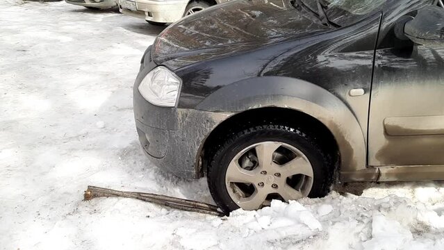 The car is stalling in the snow. A wheel is stuck in the sego