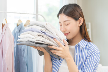 Feel softness, hygiene. Smile asian young woman touch fluffy white shirt smelling fresh clean pile,...