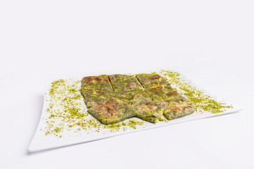 Traditional Turkish dessert Katmer with clotted cream and dough on plate isolated on white background. Prepared with thin dough, green ground pistachio and sherbet. Dessert of Gaziantep region.