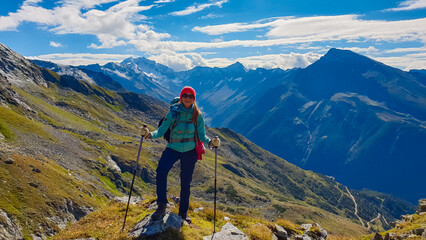 Hiker woman on alpine meadow with panoramic view of majestic mount Hochalmspitze in High Tauern National Park, Carinthia, Austria. Idyllic hiking trail in Austrian Alps. Wanderlust paradise Mallnitz - obrazy, fototapety, plakaty