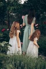 maternal care, care for the younger generation. rear view Mother and daughters in a flower garden