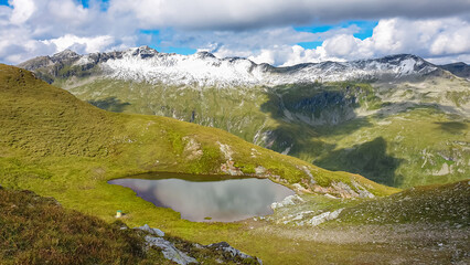 Idyllic alpine lake with panoramic view of majestic snow capped mountain peak Mallnitzriegel, High...