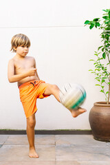 Blonde Caucasian girl, 9 years old, kicking a soccer ball. Vertical with copy space.