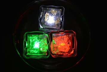 Beautiful, stylish photo of parties, celebrations, one glass champagne glass with glowing plastic ice cubes in drinks that glow with green, red and white light.