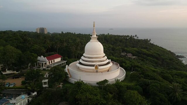 White pagoda buddhist temple among the jungle. Japanese Peace Pagoda in Sri Lanka aerial view.