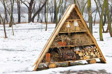 Hotel for insects in a winter park on the river bank. - 738768777