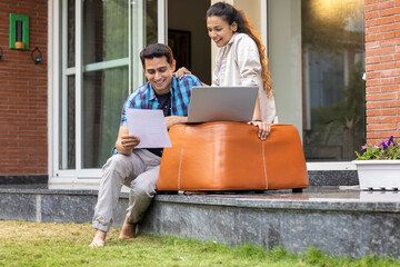 Smiling young couple using laptop while sitting together at home