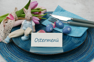 Tischkarte Ostermenü mit Teller, Besteck und Osterdekoration.