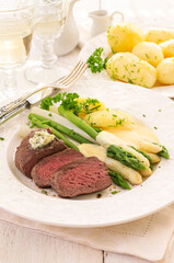 Traditional roasted angus beef steak with with white asparagus, boild potatoes and fresh salad served as close-up on a classic plate