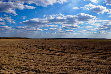 A barren landscape with ploughed earth and cloudy skies.