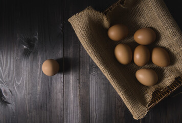 Stack of eggs in the basket on rustic wood background.