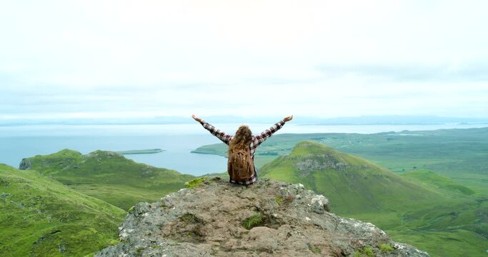 Woman, hiking and mountain cliff in environment at ocean or countryside valley or wilderness, explore or view. Female person, arms up and green hills on vacation or adventure trip, meadow or Ireland