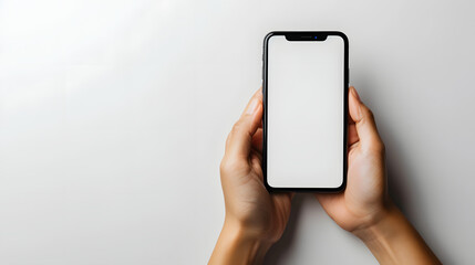 A person's hand holding a cell phone with a white screen against a white background.
