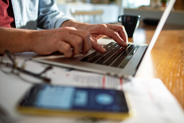 Close up of a man typing on the laptop doing online banking