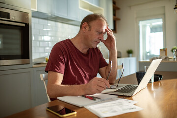 Stressed man going over bills at home