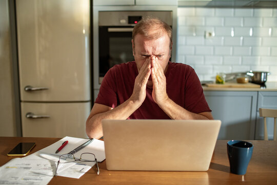 Stressed man going over bills at home