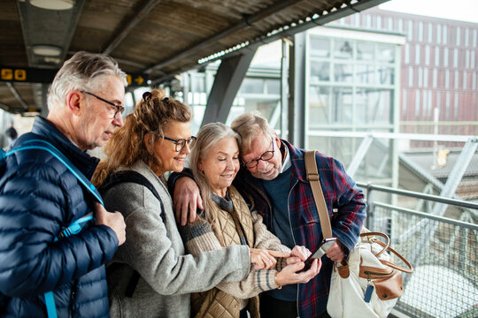 Group of senior people using smartphone together at train station