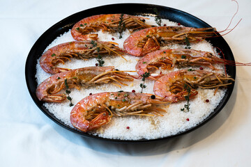 Close-up of juicy freshly grilled shrimps on coarse salt with red pepper