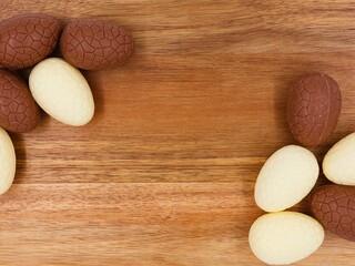 Chocolate Easter eggs on a wooden background with copy space. White chocolate and milk chocolate eggs.