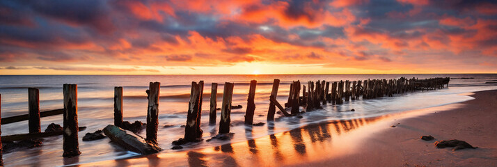 A tranquil scene of a broken wooden jetty stretching out into the golden sea - 738801784