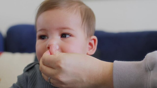 Mother wipes boogers from a baby boy's face