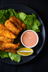 Deep-fried pike perch fillet with sauce. on a black wooden background.