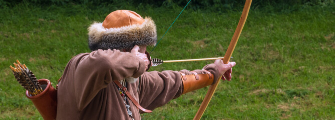 Old viking archer with oak long bow dressed with  leather fur hat.
