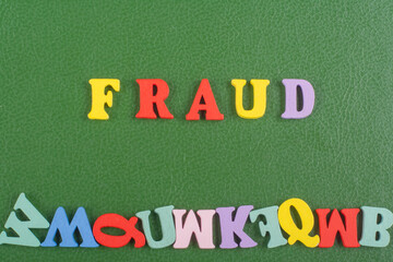 FRAUD word on green background composed from colorful abc alphabet block wooden letters, copy space for ad text. Learning english concept.