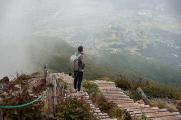 Asian man hiking in the Japan Alps mountains during summer vacation with a backpack and hiking...